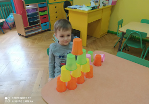 Chłopiec podczas układania kolorowych kubków wg podanego wzoru